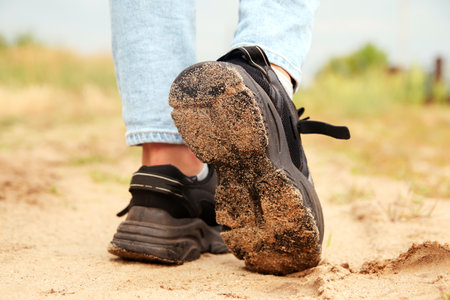 Fashion designer women's sneaker with high sole. Female sports black shoe on sand desert background....
