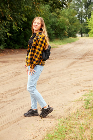 Portrait preteen girl on the green nature background. Girl 15 years old. Blonde long hair. Forest, woods. Attractive teenager. Smiling teen girlの写真素材