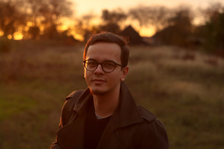 Young man 20s portrait outside wearing eyeglasses. Fall autumn background. Stylish young man....