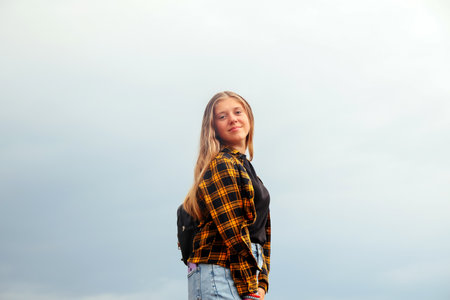 Smiling happy girl. Portrait preteen girl on the gray sky background. Girl 15 years old. Blonde long...