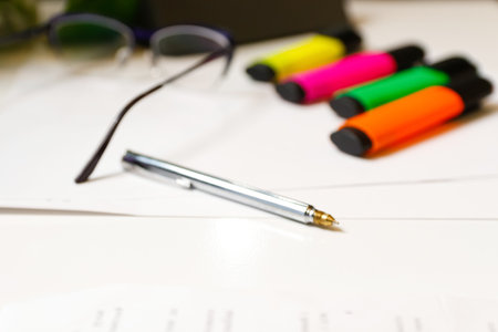 Collection of silver pen and colorful markers elegantly arranged on a clean white desk. Quality...