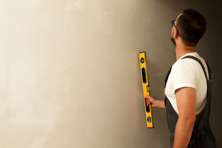 Professional using level tool on wall, clean background, excellent for border designs and mockups....