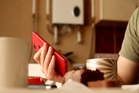 Red phone in hand, casual lifestyle, lunch table atmosphere. Lifestyle image of phone in hand.の写真素材