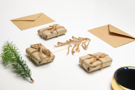 Eco-friendly Christmas background with craft gifts and festive cards. Christmas tree crafted from rope, jute, twine, and a wooden match, set against a white background.の写真素材