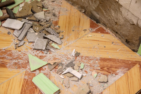 A poignant image of a ruined bathroom, where a once vibrant yellow and green tiled floor and matching wall now reveal the passage of time and neglect.の写真素材