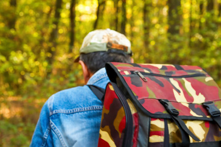 A man with a big backpack is walking through an autumn forest in Espoo, Finland. This scenic image...