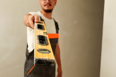 close-up of a construction worker in overalls showing the yellow correct building level.  house...
