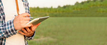 a farmer hand holding a tablet in a field. Banner for design with copy space. farmer with tablet...