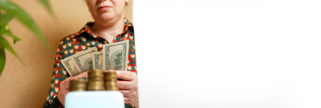 banner image symbolizing business success and wealth. A professional woman's hands are shown actively counting stacks of dollar money, cash, emphasizing financial growth and success.の写真素材