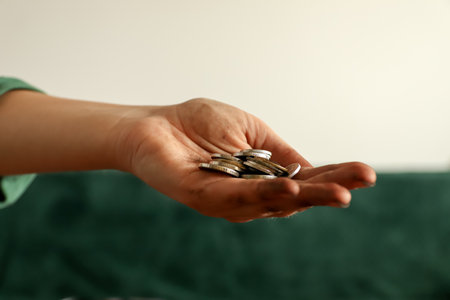 Close-up of a dirty hand holding a small pile of silver coins. Concept of poverty or hard-earned money.の写真素材