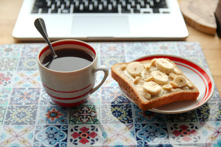 Healthy breakfast at home office. Cup of black coffee and toast with peanut butter and banana on a...