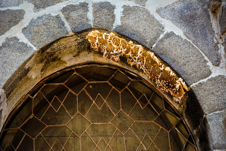 An abandoned honeycomb in a mosque's window. An old arch from 16th century, named Kushumba Mosqueの写真素材