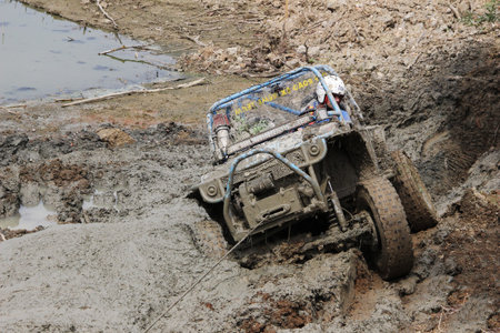 Off-road vehicle scaling uphill through mud with car winchのeditorial素材