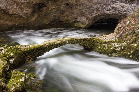Old stone bridge coverd with moss and torrential riverの写真素材