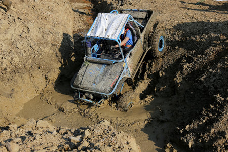 Offroad car driving downhill to deep mud by pulling with car winch on offroad race.