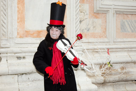 Male Pierrot playing violin with red rose on San Zaccaria Square, Venice, Italy - Venice Carnivalのeditorial素材