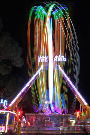 Spinning ferris wheel in the night with coloured lights trails.のeditorial素材