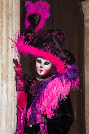 Cat mask - Female Venetian Mask in pink / black elegant costume on St. Mark's Square in Venice with traditional venetian pillar - Venice Carnivalのeditorial素材