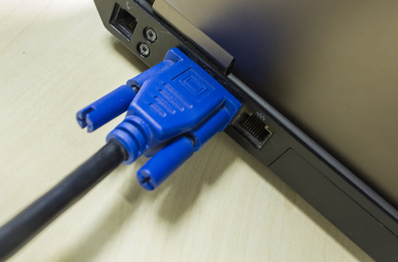 VGA cable connected to laptop on wooden tableの写真素材