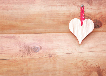 Bright heart on the brown wooden wall right. Valentines day card background. Copy space.の写真素材
