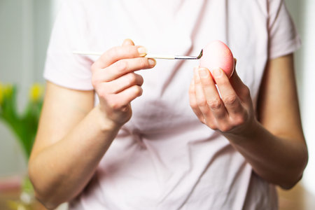 Young beautiful woman painting an Easter egg. Happy easter. Close-up. Copy space.の写真素材