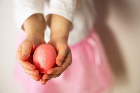 Girls hands holding one pink Easter egg. Happy Easter. Preparation for Easter and spring.の写真素材