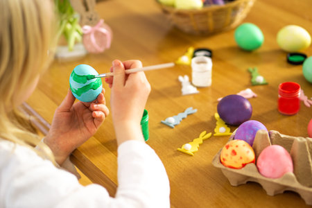 Lettle child hands painting Easter eggs on wooden table. Preparation for Easter celebration.の写真素材
