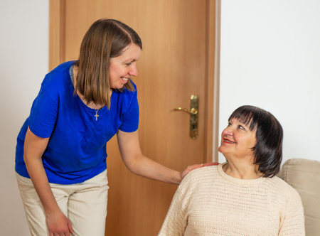 Young caregiver helping senior woman at home. Caring nurse assisting her middle aged female patient.の写真素材