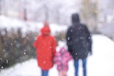 Back view portrait of happy family with child in winter park out of focus.の写真素材