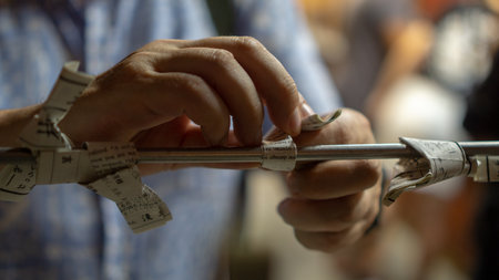 Tokyo, Japan - August 2018: Close up of an unidentified man's hands tying a knot with Omikuji - Paper Fortune at Sensoji Asakusa Kannon Temple at nightのeditorial素材
