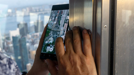 Tokyo, Japan - August 2018: Man holding Samsung phone taking photo of the city from Tokyo Tower