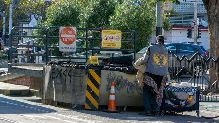 San Francisco, USA - August 2019: A homeless man with denim jacket checking garbage for clothes