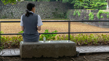 Tokyo, Japan - August 2018: Young Japanese woman with a pony tail having her lunch on a benchのeditorial素材