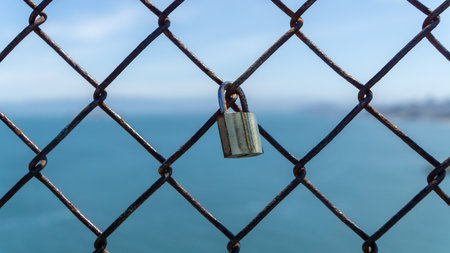 San Francisco, USA - August 2019: Shiny metal padlock on a fence symbolizing love and commitmentの写真素材