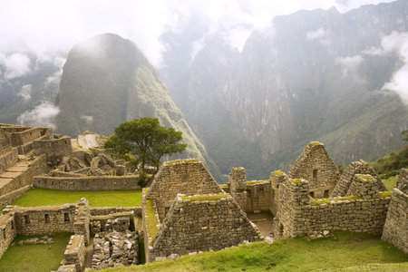 Ancient ruins of Machu Picchu near Cusco, Peru with foggy backdrop.