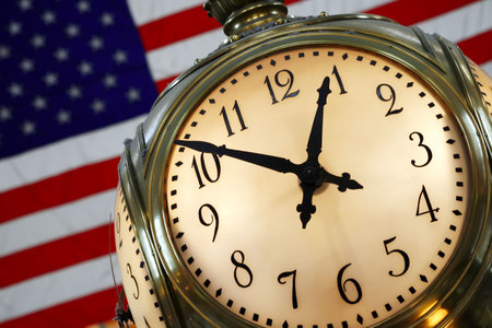Clock atop information booth in Grand Central Station with American flag in the background.の写真素材