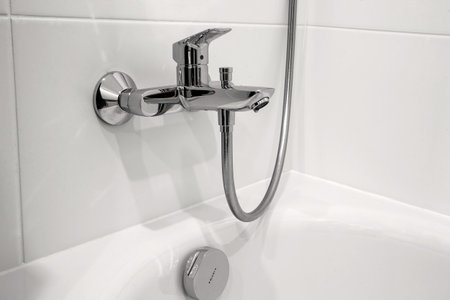 steel tap water in the bathroom on a background of white tilesの写真素材