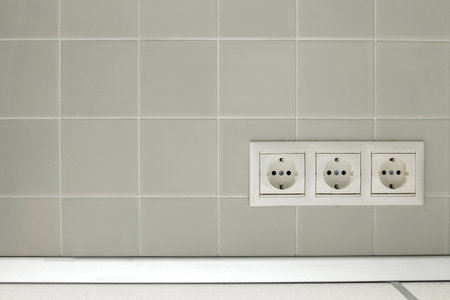 Three white electric on a white wall tilesの写真素材
