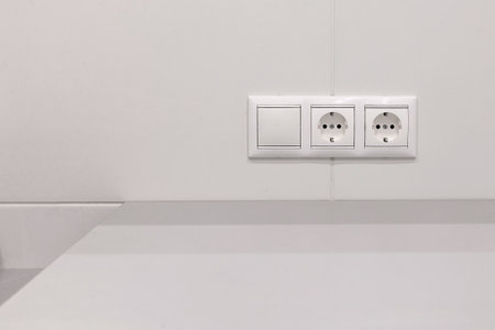 two electrical sockets with a switch on a white wallの写真素材