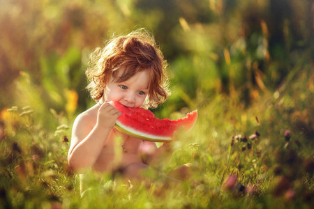 Two flying little boy eating watermelon in the meadowの写真素材