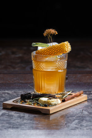cold summer cocktail on a wooden dinette decorated with honeycomb and ice on a dark backgroundの写真素材