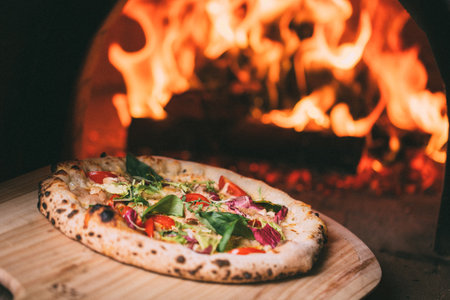 Taking tasty pizza out of oven in restaurant kitchenの写真素材