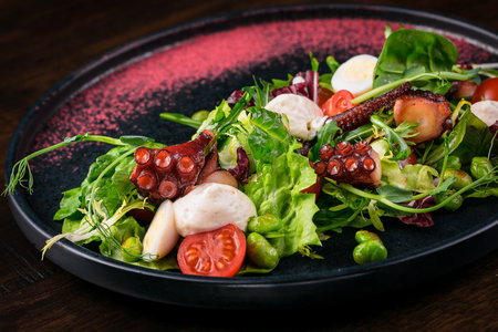 quail eggs salad with tomatoes and microgreen octopus scallops on a dark backgroundの写真素材