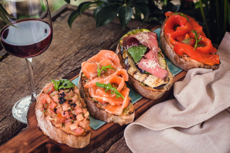 different bruschetta on a wooden board with a glass of wineの写真素材