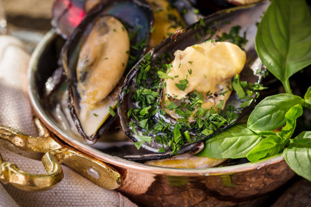 delicious cooked mussels with basil and cheese close-up in a beautiful panの写真素材