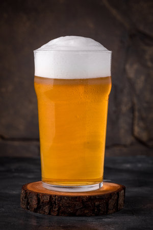 a glass of cold light beer in a mug on a dark backgroundの写真素材