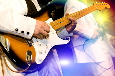  The guitar-player plays an electroguitar, the second person with a microphone on a background, bright multi-coloured lightの写真素材