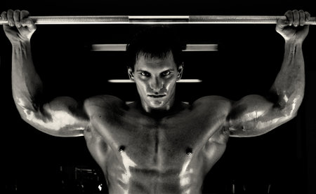 very power athletic guy ,  execute exercise tightening  on horizontal bar, in  sport-hall, glamour...