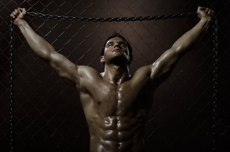 the very muscular handsome weary sexy guy ,  on  netting   steel fence with steel chainの写真素材