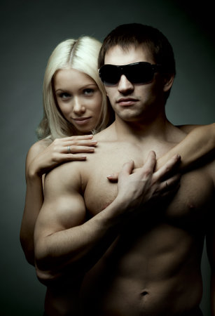 muscular handsome sexy guy with pretty woman on dark backgroundの写真素材
